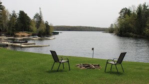 En vy över sjön med två stolar som är placerade så att de vetter mot vattnet, en brygga med båtar och ett gräsområde.