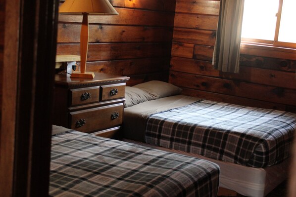 A cabin-style room with two beds, a dresser, and a lamp. - Dun Rovin Duplex1 On the Chippewa Flowage (Hayward)