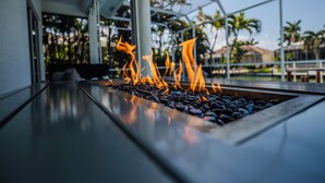 A fire feature with a metal frame and a flat surface with black stones. - Marco Island Waterfront Single-Story Home w/ Direct Gulf Access (Marco Island)