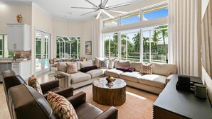 A spacious living room with a large sectional sofa, a coffee table, and a ceiling fan. - Marco Island Waterfront Single-Story Home w/ Direct Gulf Access (Marco Island)