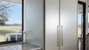 A modern kitchen with a large refrigerator, a dishwasher, and a window with a view of a field. - Breathtaking modern 100 acre ranch on the Colorado River. Weddings available (Smithville)