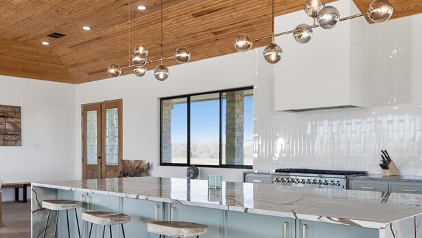 A modern kitchen with a large island, bar stools, and pendant lighting. - Breathtaking modern 100 acre ranch on the Colorado River. Weddings available (Smithville)
