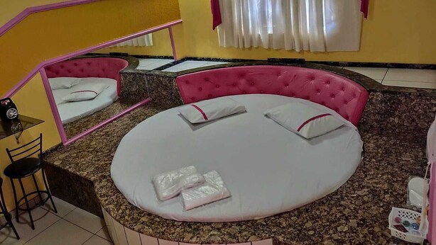 A room with a round bed, a small table, a chair, and a mirror. - HOTEL PARAÍSO  (Guaira)