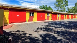 A row of single-story motel rooms with red and yellow exterior walls, numbered doors, and a gravel driveway. - HOTEL PARAÍSO  (Guaira)