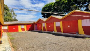 A row of red and yellow buildings with numbered doors, a gravel ground, and a clear sky. - HOTEL PARAÍSO  (Guaira)