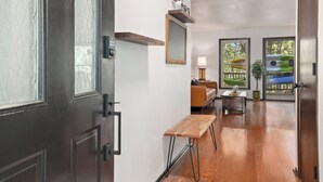 A modern interior with a wooden bench, a small table, a mirror, and a lamp.