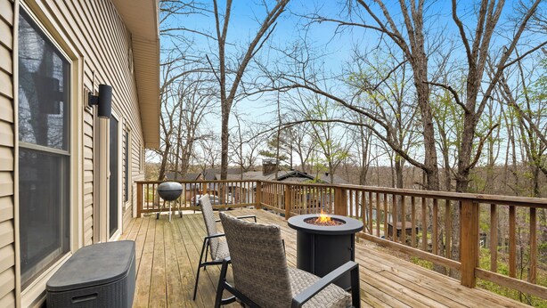 A wooden deck with outdoor furniture, including a chair and a table, and a fire pit.