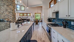 A modern kitchen with a stone accent wall, a central island, and a dining area with a fireplace.