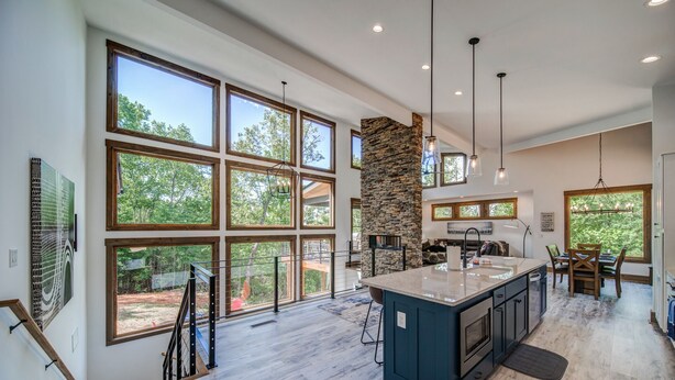 A spacious kitchen with large windows, a central island, and a stone accent wall.