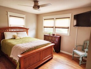 Ein Schlafzimmer mit einem hölzernen Bett, einem Deckenventilator, einem Schminktisch und einem Stuhl.