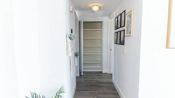 A narrow hallway with a wooden floor, white walls, and a door leading to a room with a sliding door.