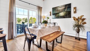 A dining area with a table set for four, a bench, and a view of the outdoors. - Shamrock by the Sea Hot Tub Arcade Basketball Court & Beach Fun (Wells)