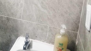A bathroom with grey tiles, a white sink, and a bottle of hand soap. - hotel 51b (Bogotá)