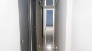 A narrow, well-lit hallway with tiled flooring and a door on the left. - hotel 51b (Bogotá)