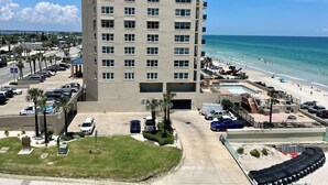 Un hôtel de grande hauteur offrant une vue sur la plage, avec un parking et un espace piscine.