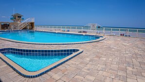 Une piscine dotée d’une tour de surveillance pour les sauveteurs, d’une terrasse ensoleillée et offrant une vue sur l’océan.