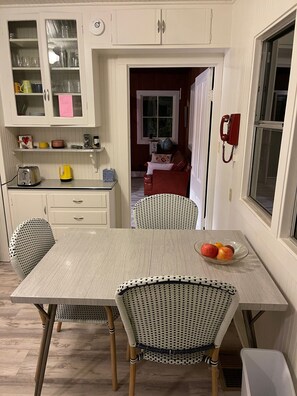 Enjoy casual dining at this kitchen's central island table, surrounded by wicker chairs and a vintage rotary phone.