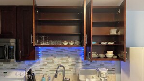 A kitchen with a double sink, a microwave, a stove, and open cabinets with dishes and glasses. - 2bedrm/1bathrm, near shopping center and freeway  (Honolulu)
