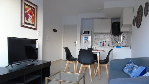 Una sala de estar moderna con un televisor de pantalla plana, una mesa de centro y un sofá con un cojín decorativo.
