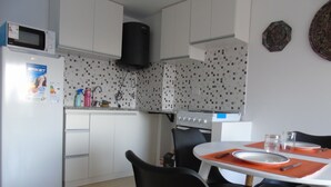 Una cocina compacta con armarios blancos, microondas, estufa y comedor con mesa y sillas.
