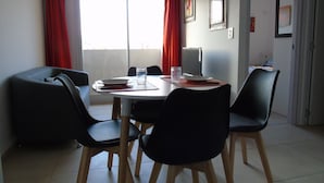 Un comedor con una mesa redonda, sillas negras y un ventanal con cortinas rojas.