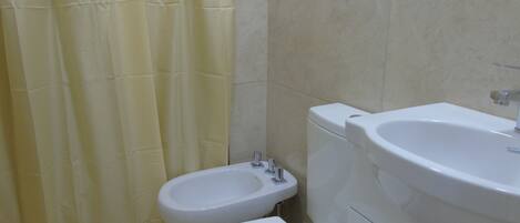 Une salle de bain équipée de toilettes, d’un bidet et d’un lavabo.
