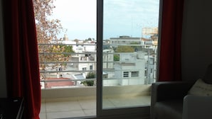 Una habitación con un ventanal grande, un sofá y vistas a edificios y árboles.