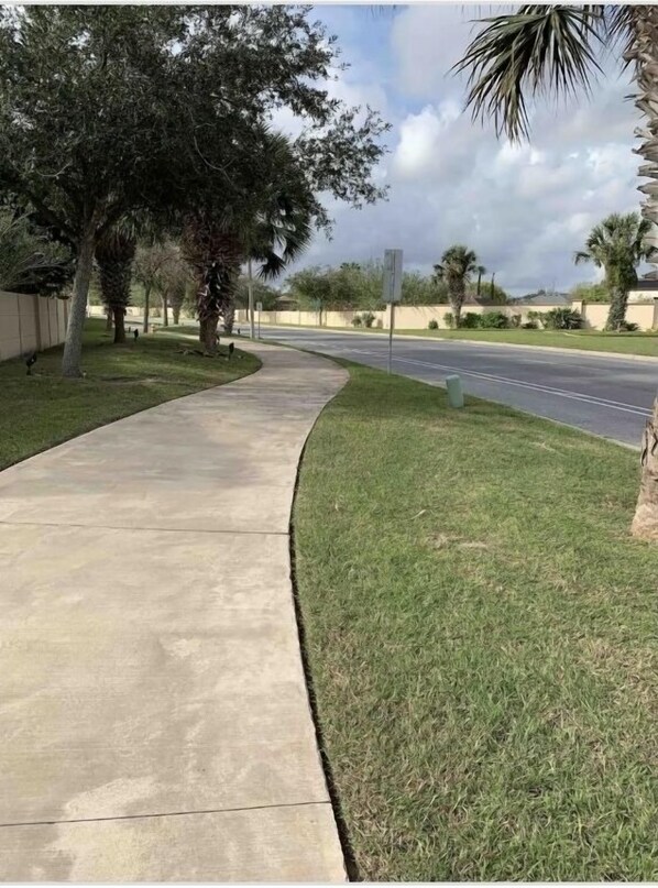 A sidewalk curving along a road with a grassy area on one side and trees on the other. - Peaceful & Private Studio #2 (Brownsville)