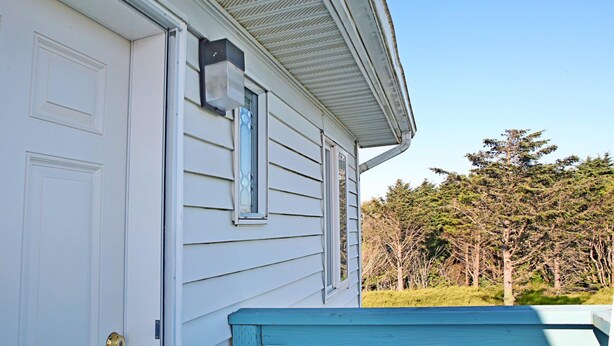 A house with a white door, a window with a decorative glass, and a blue front porch. - Sea Forever Condo at Maris Stella (Ocean Shores)