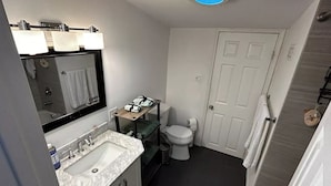 Un baño pequeño con lavamanos de mármol, tocador, inodoro y espejo.