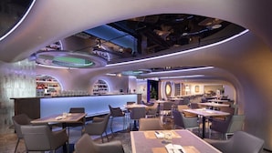 Um restaurante moderno com teto curvo, área de bar e diversas opções de assentos.