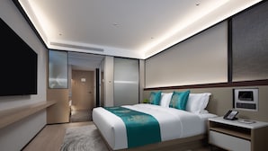 Quarto de hotel moderno com cama grande, mesas de cabeceira, televisão e closet espaçoso.