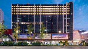 Um edifício moderno, de vários andares, com grandes janelas e sinalização iluminada.