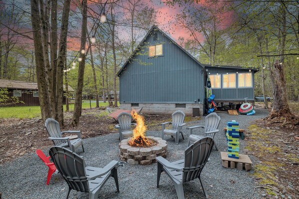 A rustic cabin with a fire pit surrounded by outdoor seating.