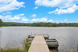 A wooden dock extending into calm water with boats docked at the end.