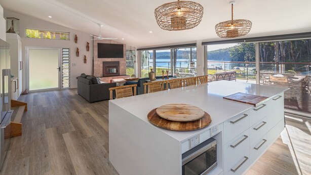 A spacious kitchen with a large island, a dining area with wooden chairs, and a view of the outdoors. - Tambo Lindo- Meaning beautiful inn in Quechua the Inca language of Perú (Smiths Lake)