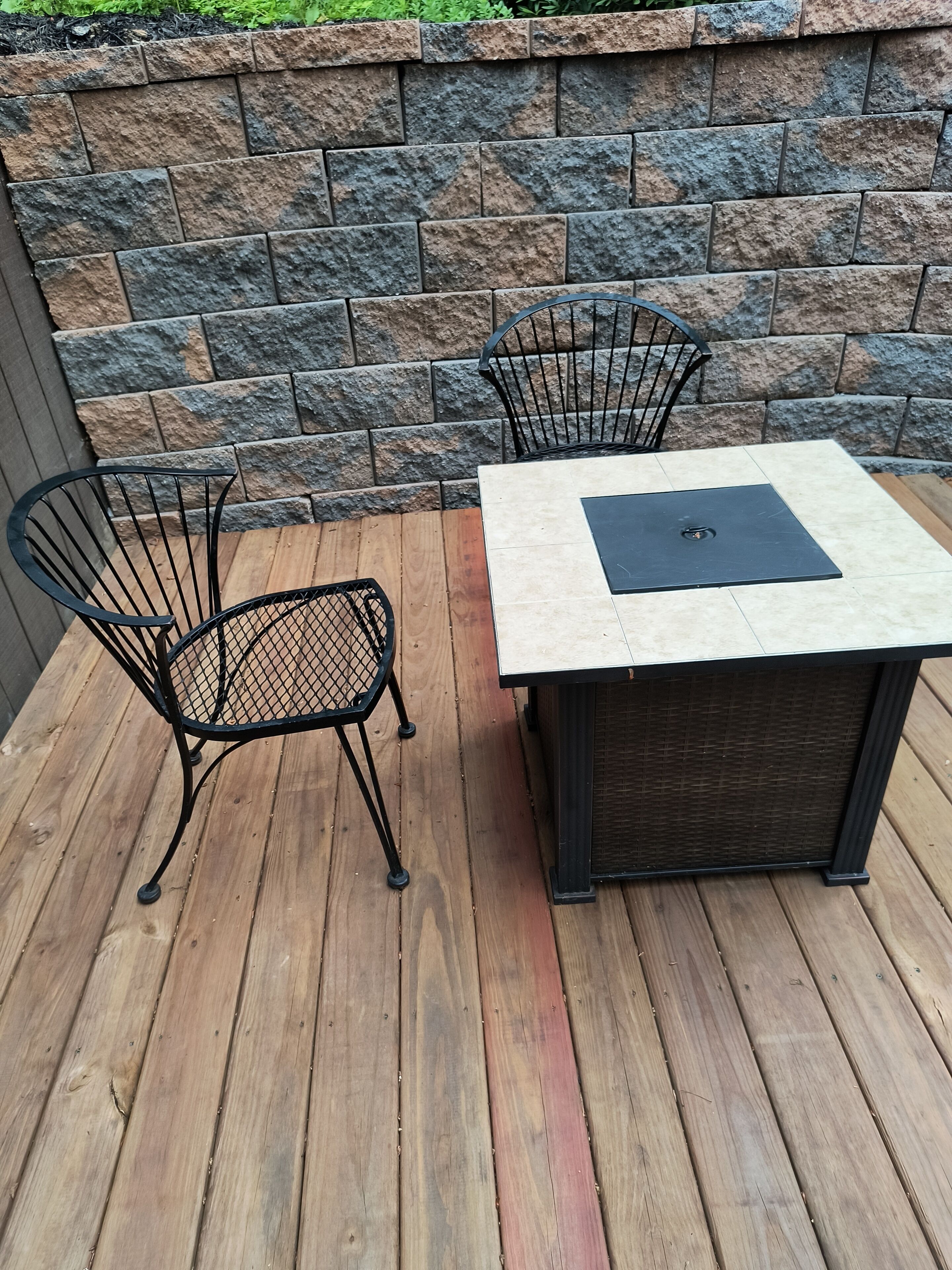 Un patio con pared de piedra, cubierta de madera y una mesa con sillas.