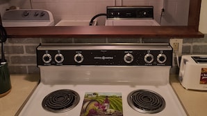 A kitchen with a white stove, a toaster, and a sign above the stove that reads "LIVE WELL LOVE MUCH LAUGH OFTEN".