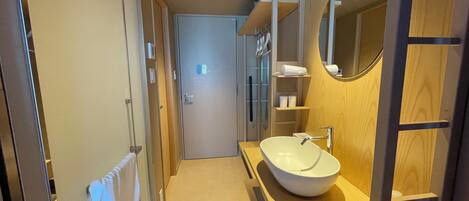 A modern bathroom with a large sink, wooden vanity, and a mirror.