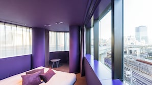 A modern hotel room with a large bed, a small seating area, and a city view through large windows. - toggle hotel suidobashi TOKYO (Tokyo)