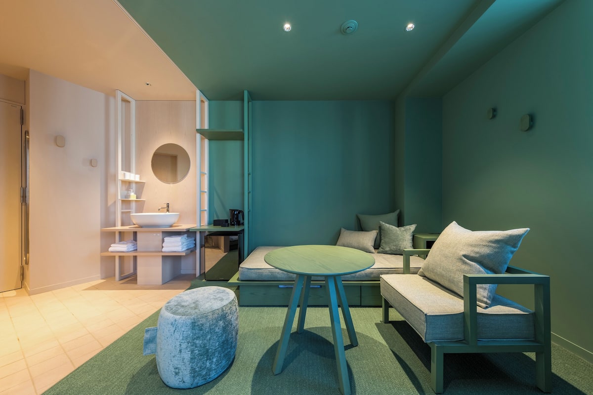 A modern, well-lit room with a sofa, ottoman, and a round table.