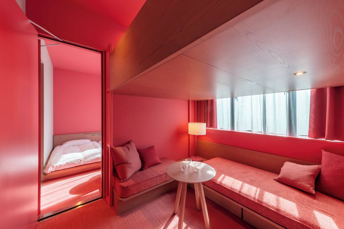 A room with a bed, a sofa, a small table, and a window with curtains.