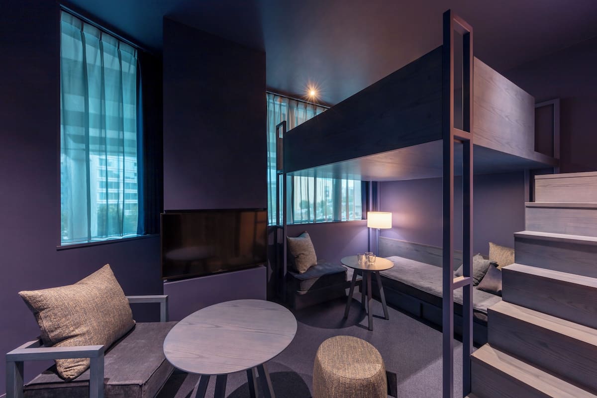 A modern room with a bunk bed, a round table, and a sofa.