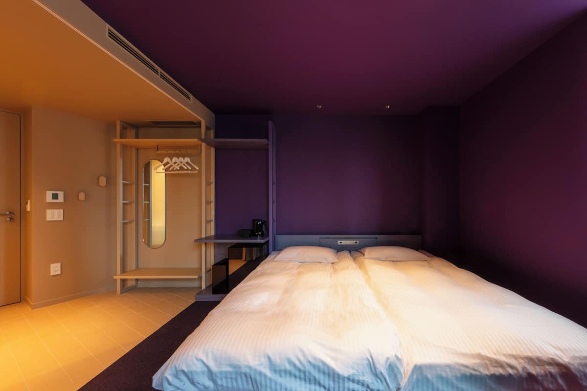 A bedroom with a bed, a desk, and a wardrobe.