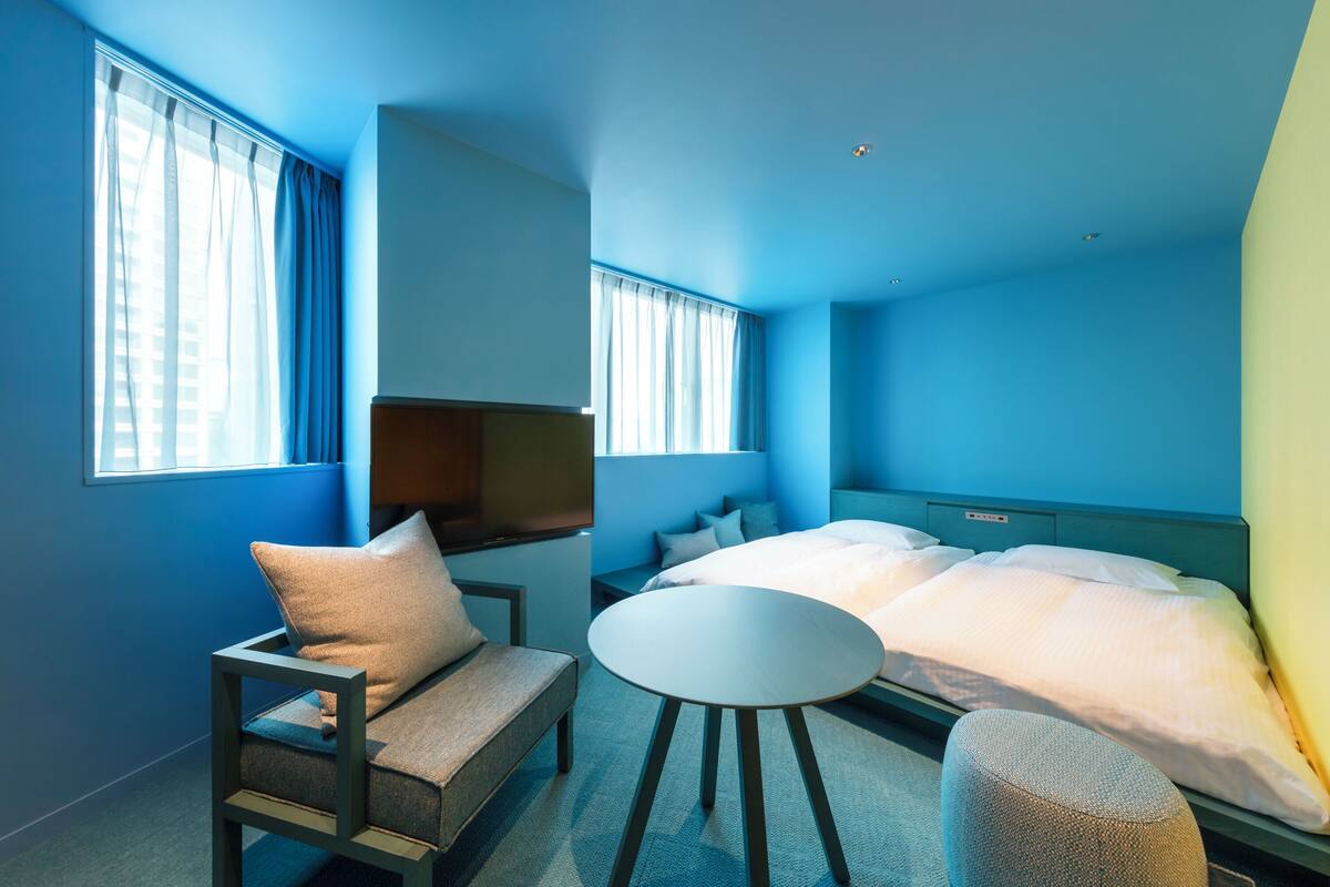 A room with a bed, a sofa, a small table, and a window with curtains.