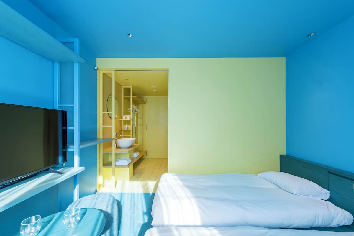 A hotel room with a bed, a TV, and a bathroom visible through an open door.