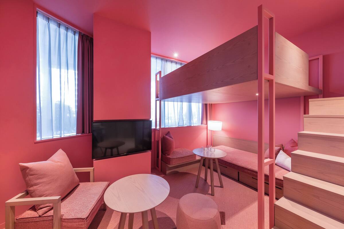 A room with a bunk bed, a TV, a sofa, a small table, and a lamp.