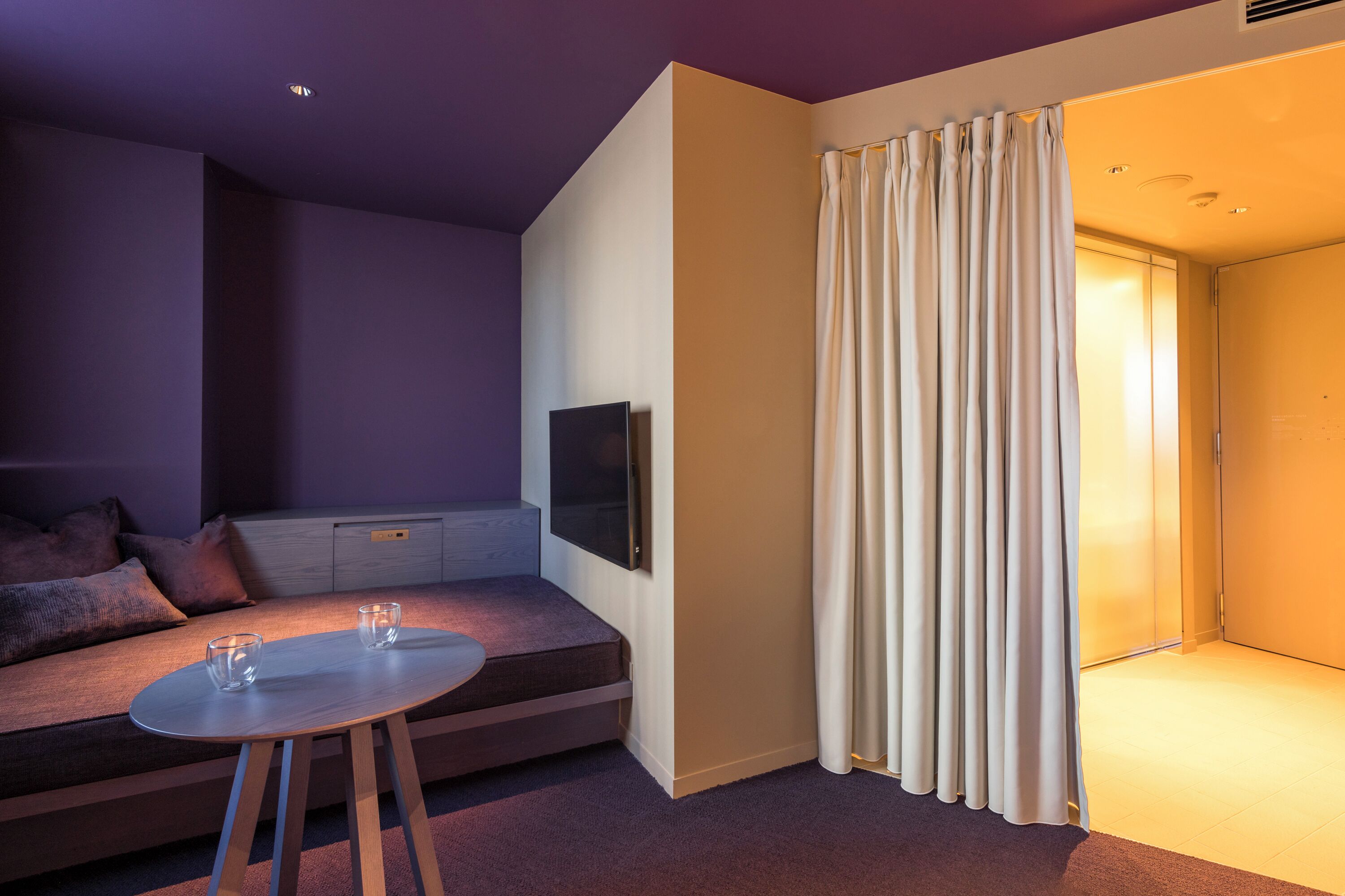 A modern room with a sofa, a small table, and a curtain.