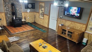 A cozy living room with a fireplace, a dartboard, a television, and a wooden coffee table. - Cannon Cliffside River Retreat-  FREE WIFI (Springfield)