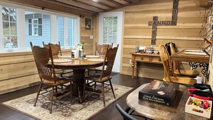 A dining area with a round wooden table, six chairs, and a chessboard on the table. - Cannon Cliffside River Retreat-  FREE WIFI (Springfield)